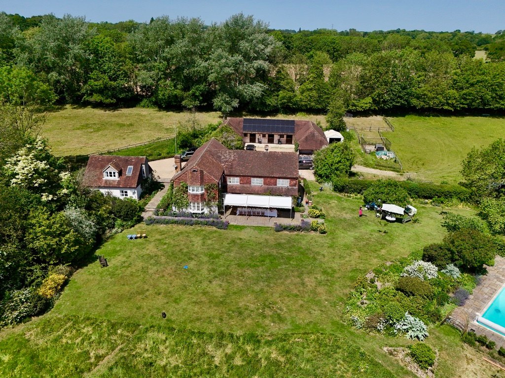 Period property with pool and gardens set among woodland, aerial view