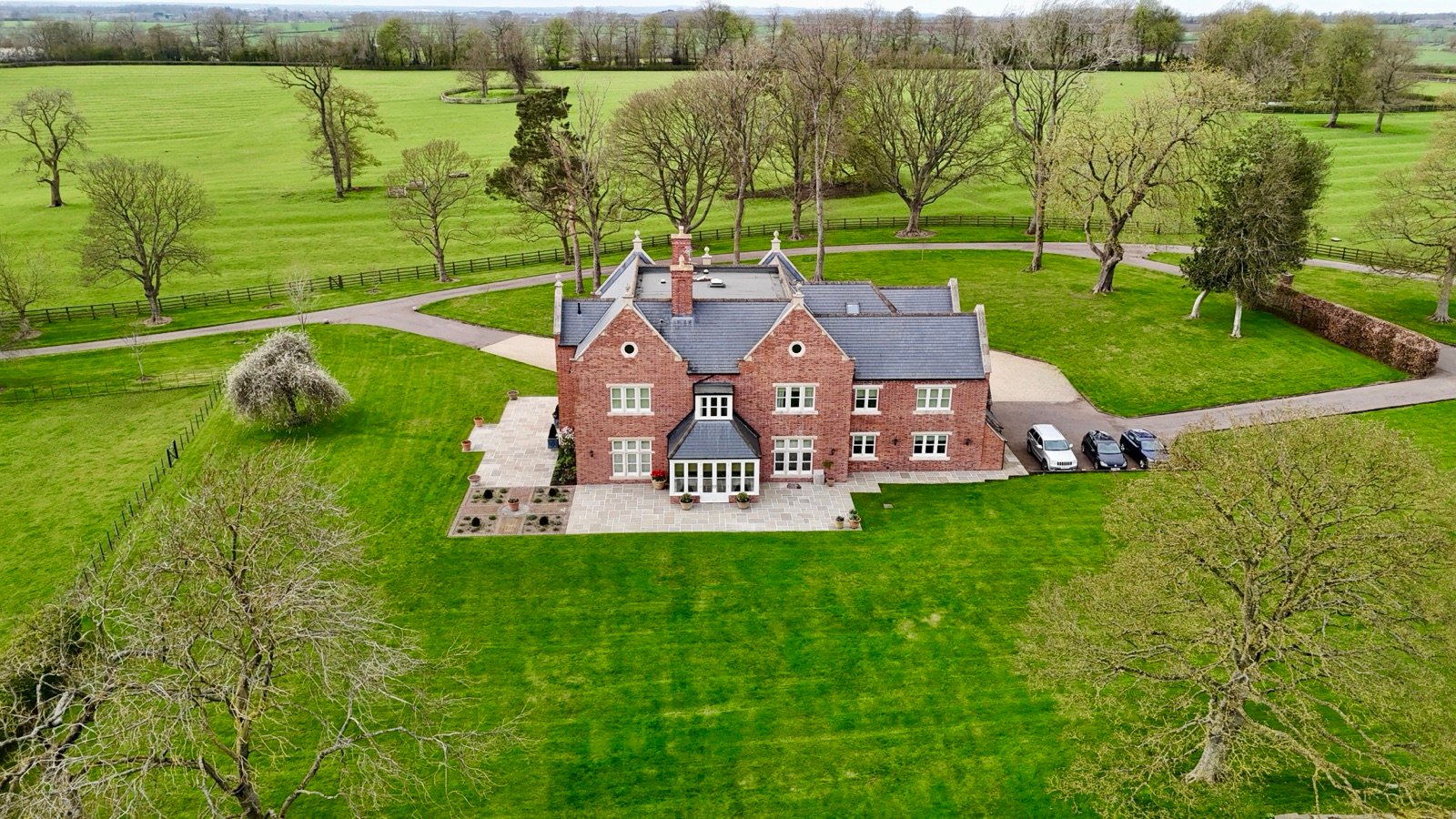 Aerial view of a red-brick country house in Rutland surrounded by parkland